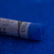  A close-up of a blue Sennelier extra soft pastel on the same coloured background, with the colour information printed on the paper wrap.