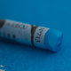  A close-up of a blue Sennelier extra soft pastel on the same coloured background, with the colour information printed on the paper wrap.