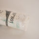 A close-up of an iridescent  White Sennelier extra soft pastel. on the same coloured background, with the colour information printed on the paper wrap.
