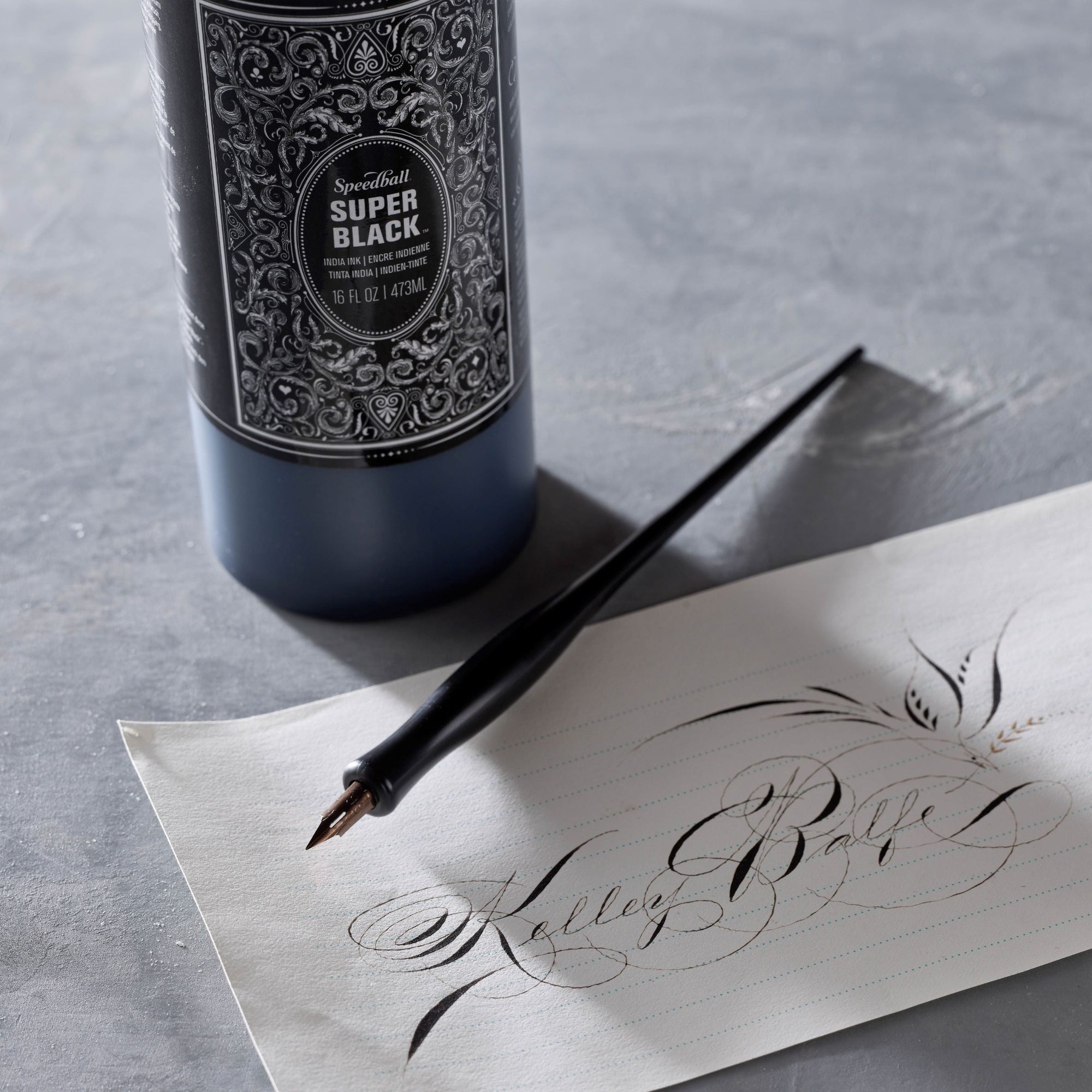 Bottle of Super Black ink with a calligraphy pen and calligraphy design  on paper