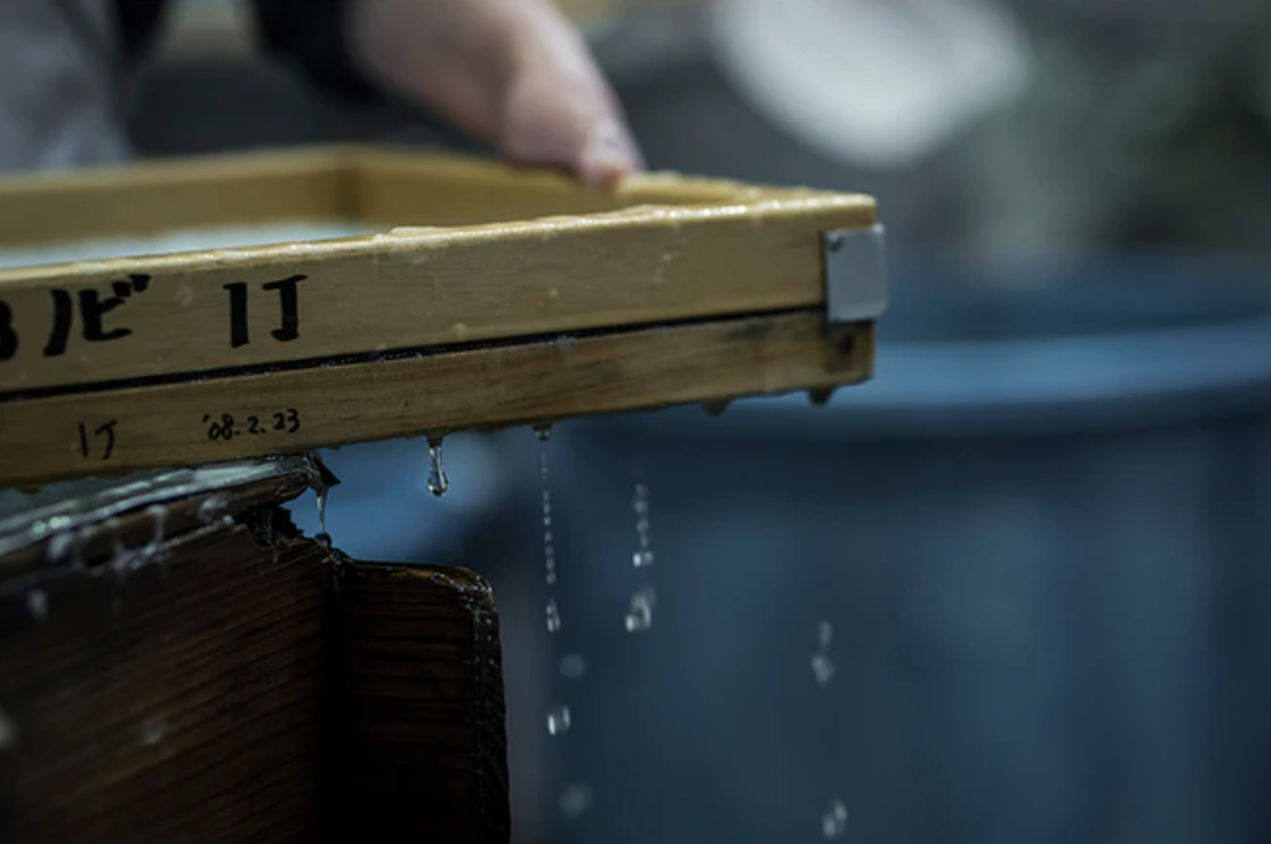The edge of a papermaking frame filled with pulp and dripping water 