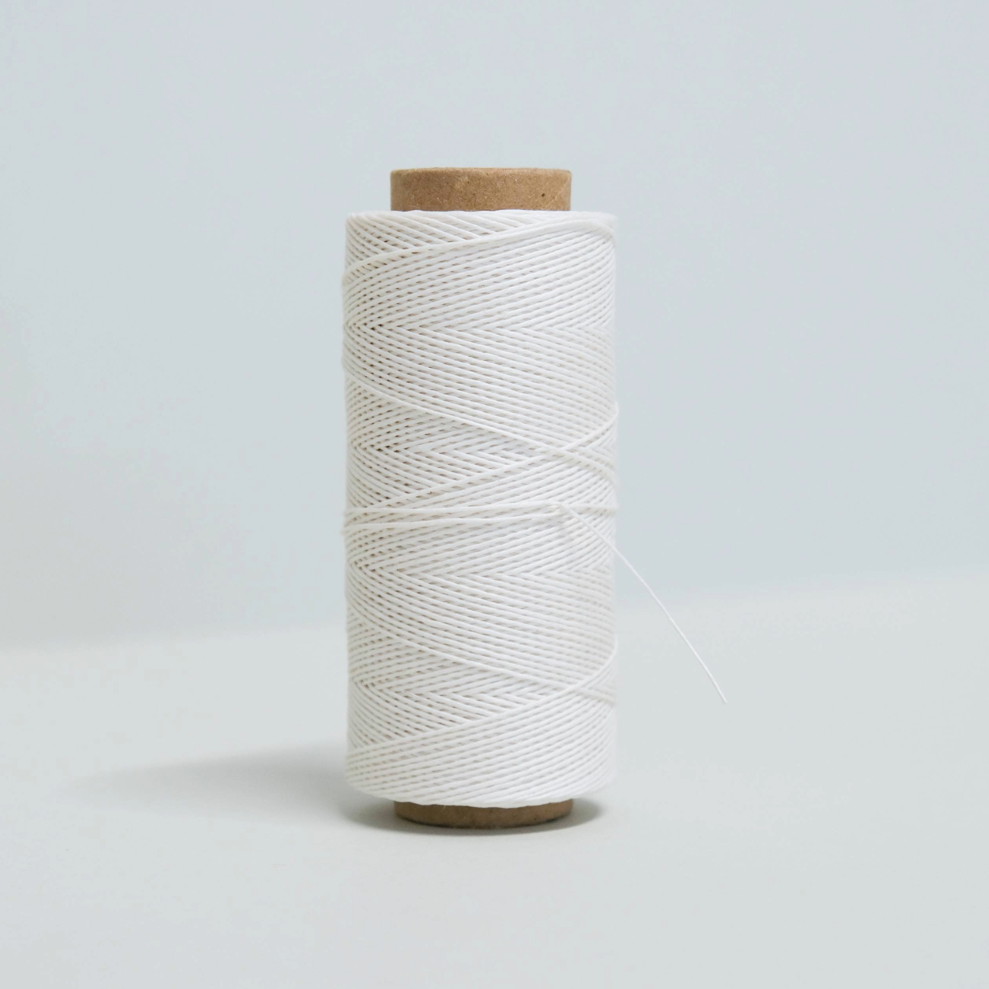 Spool of white thread on a light grey background