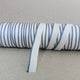 Blue and white stripped bookbinding headband on a spool against a neutral background