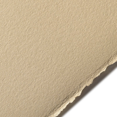 A close-up image of a piece of BFK Rives printmaking paper in a light brown colour, showing its texture and deckle edge.