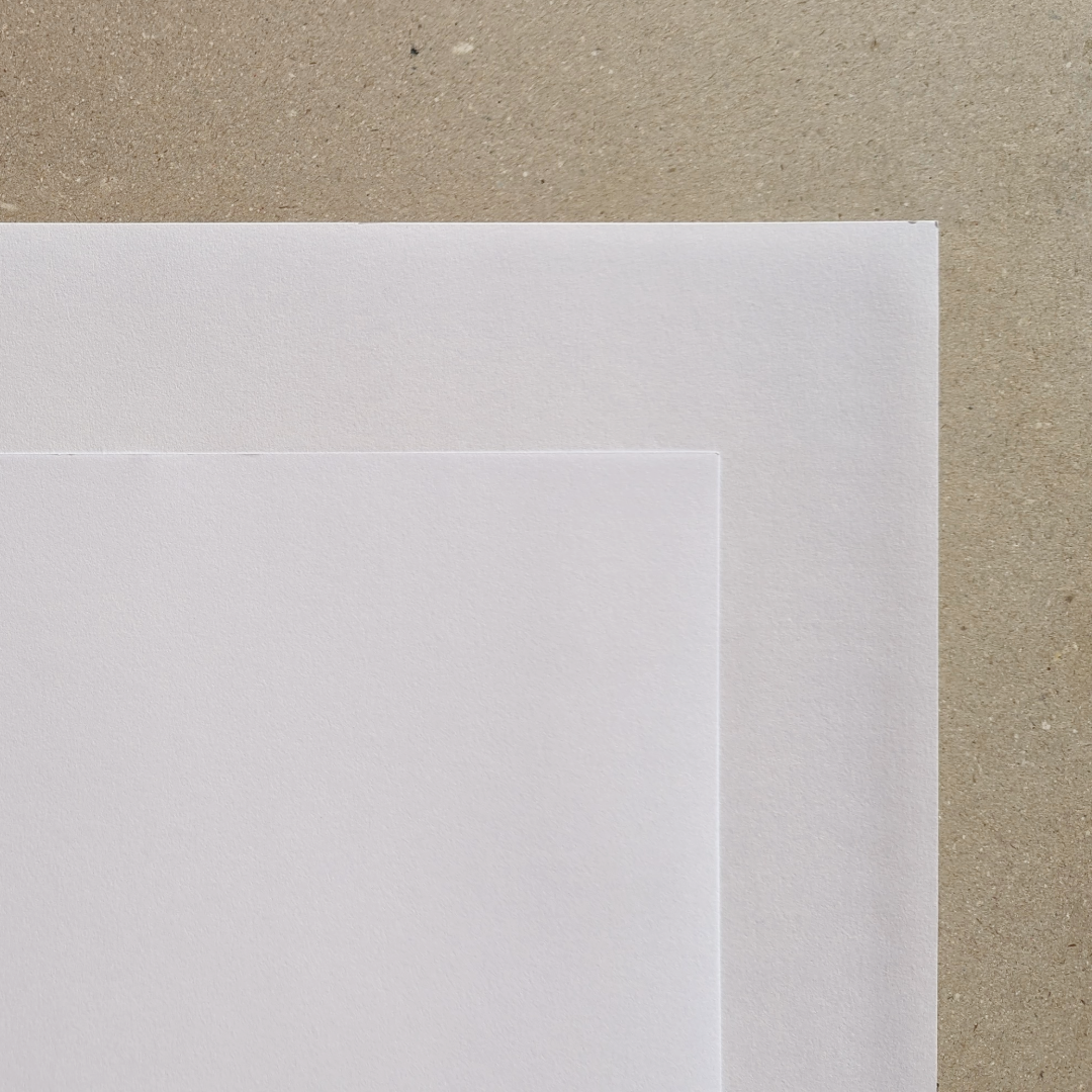 Stack of two white drawing papers with a slight texture on a beige background