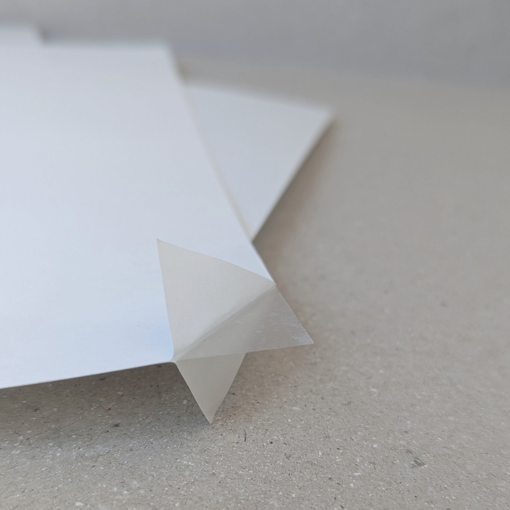 A close-up of a double sided adhesive sheet paper partially folded, showing the adhesive quality and the clear, film-like texture.