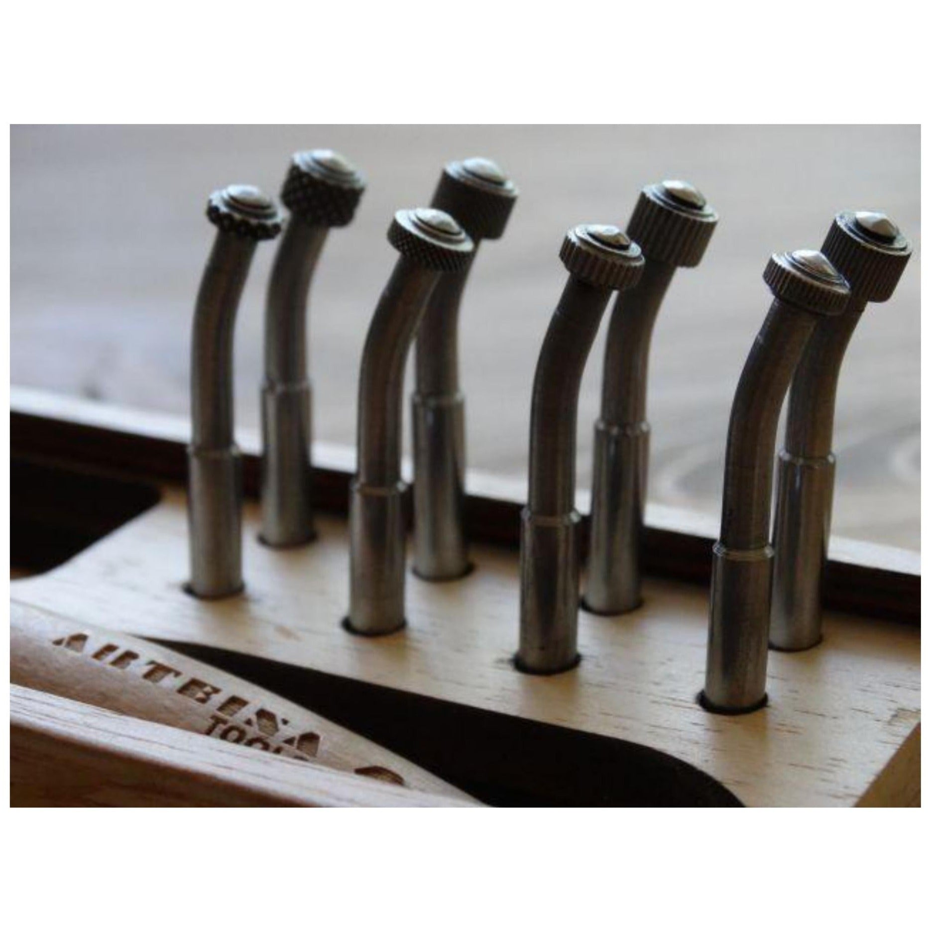 A close up of 8 Roulette heads of various widths with dotted or lined surfaces standing up in a box.