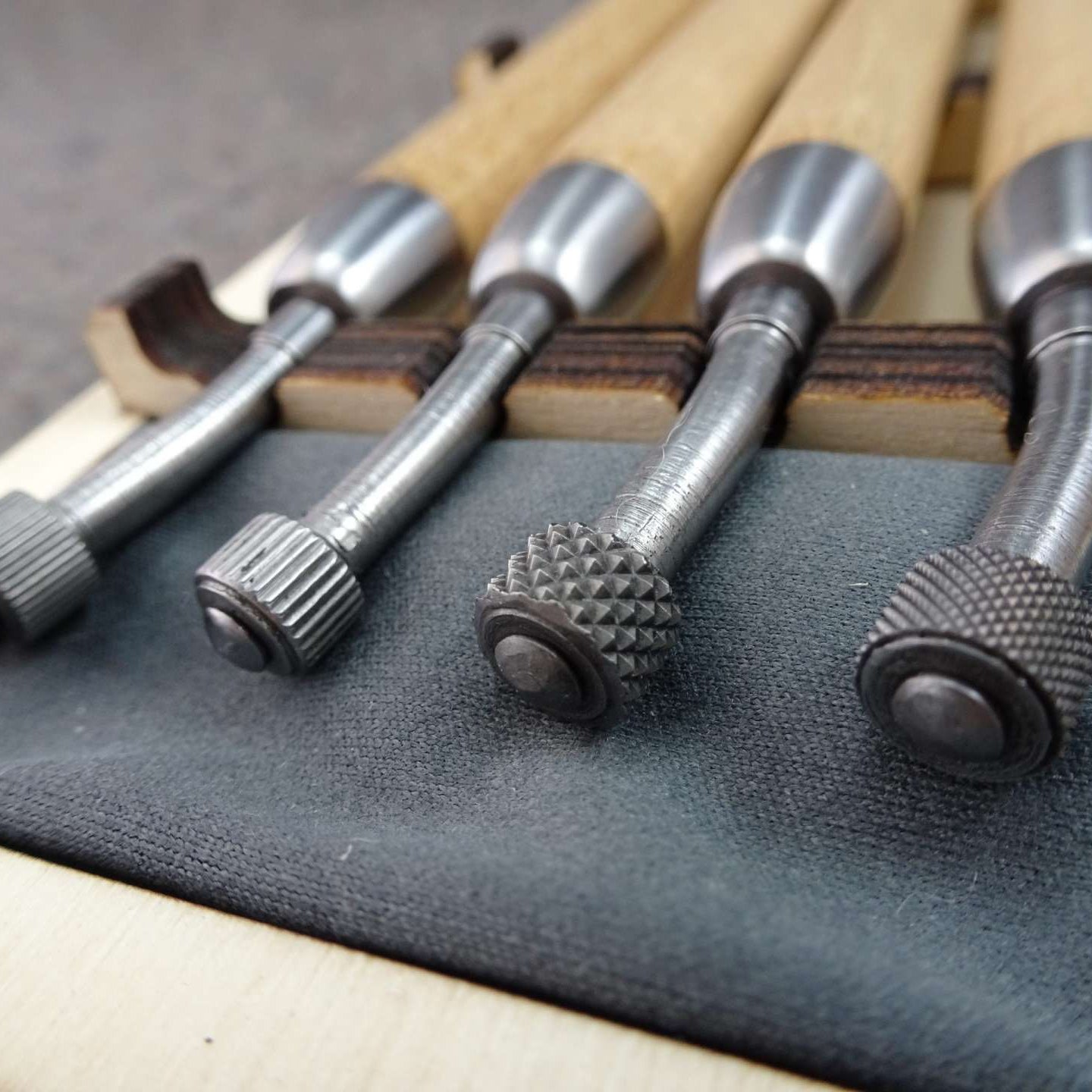 Close up of 4 metal roulette tips with wooden handles in a mix of line and dot textures.