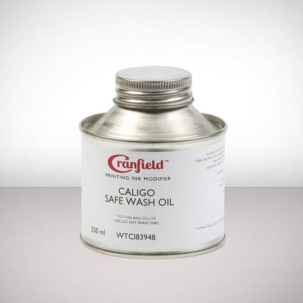 A metal tin of Caligo Safe Wash Oil with a white label against a grey background