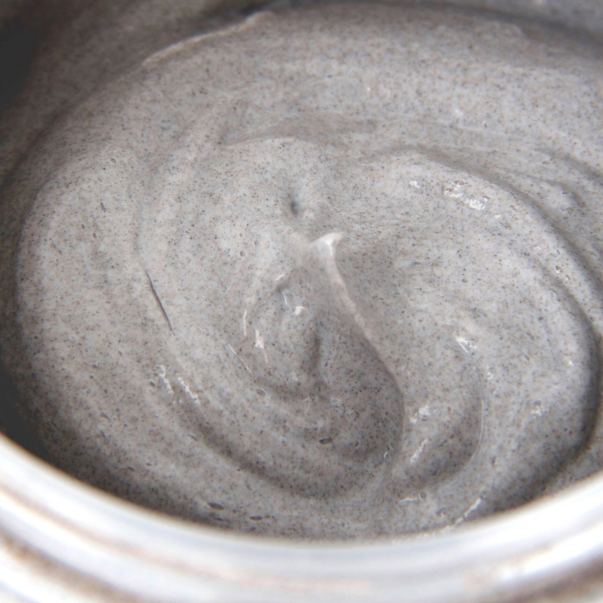 Close-up of a gray creamy substance in a container