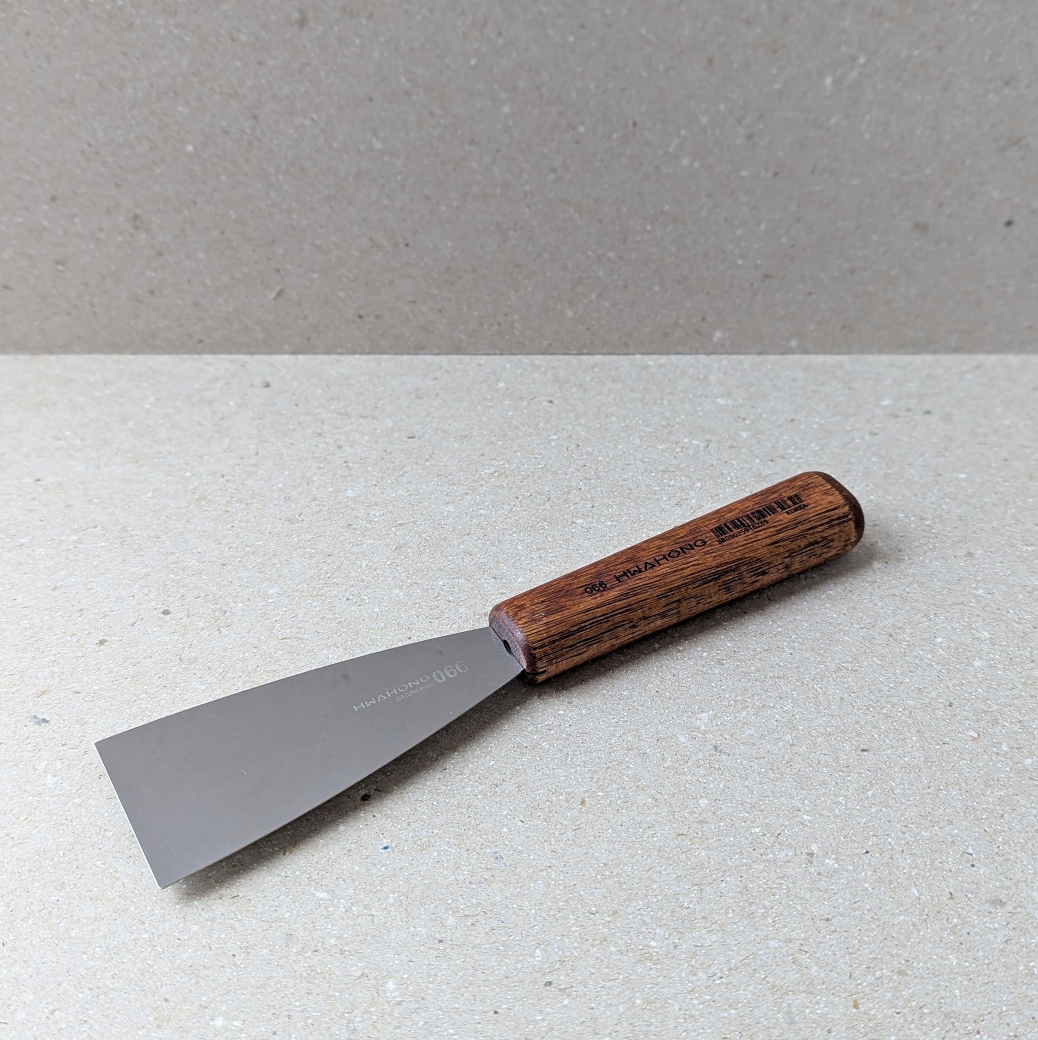 Scraper tool with wooden handle on a grey surface