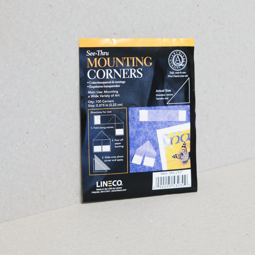 Packaging of Lineco Archival Mounting Corners with clear self-stick corners shown on the outside with a diagram for use.