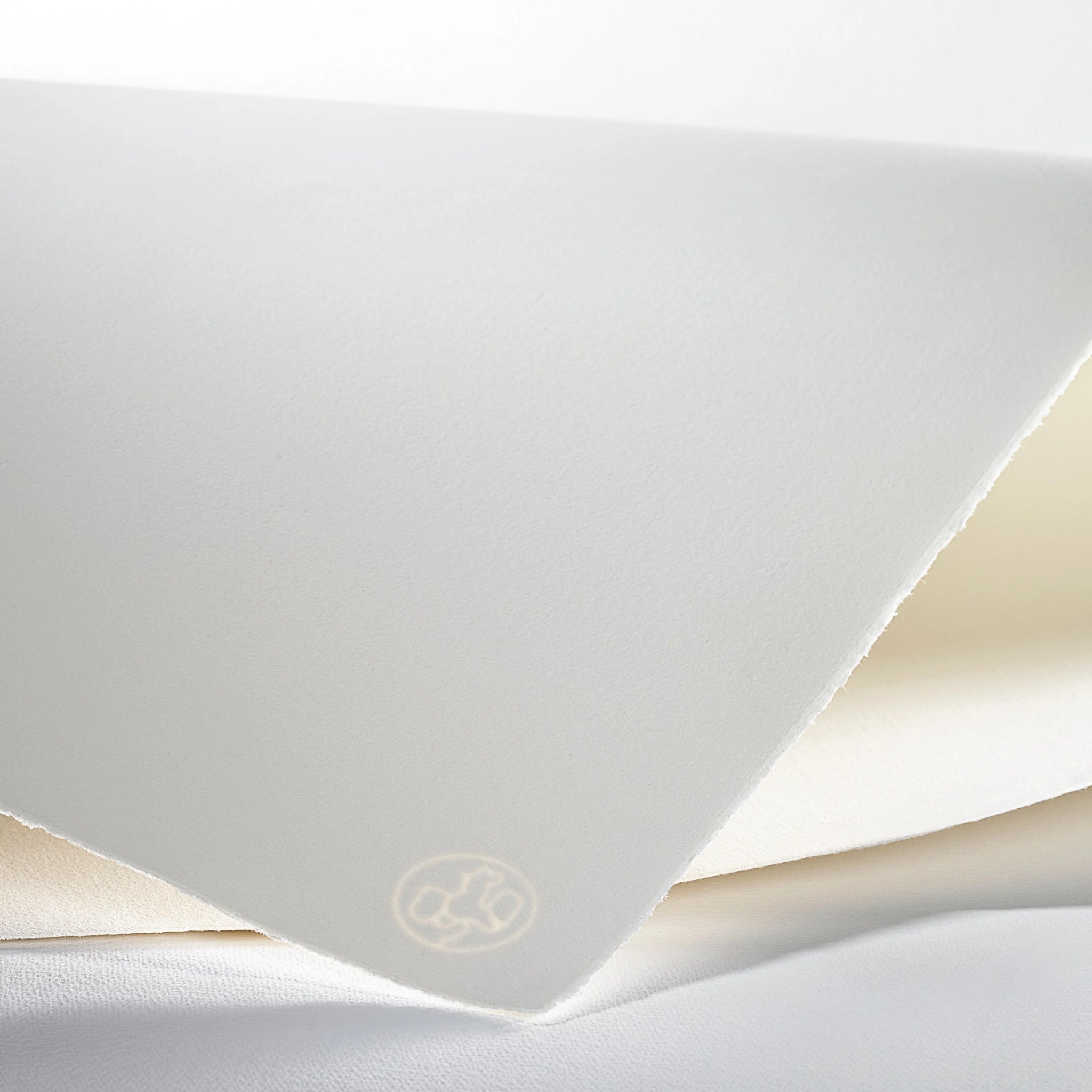 A sheet of hahnemuhle paper in a bright white loosely folded over itself showing the rooster watermark in the corner of the paper