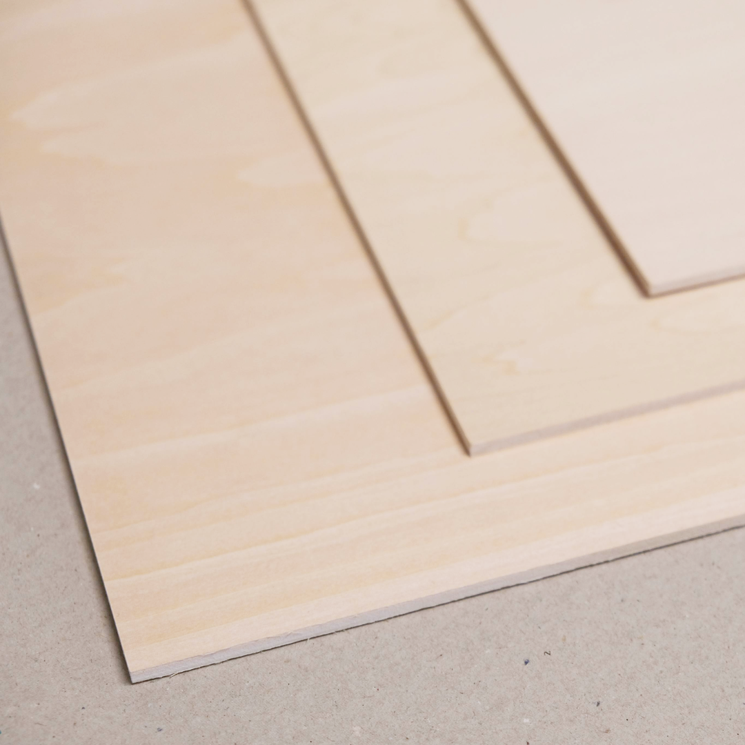 Close up on a stack of three beige plywood plates with a fine grain texture, typically used for woodcut printing, on a light background