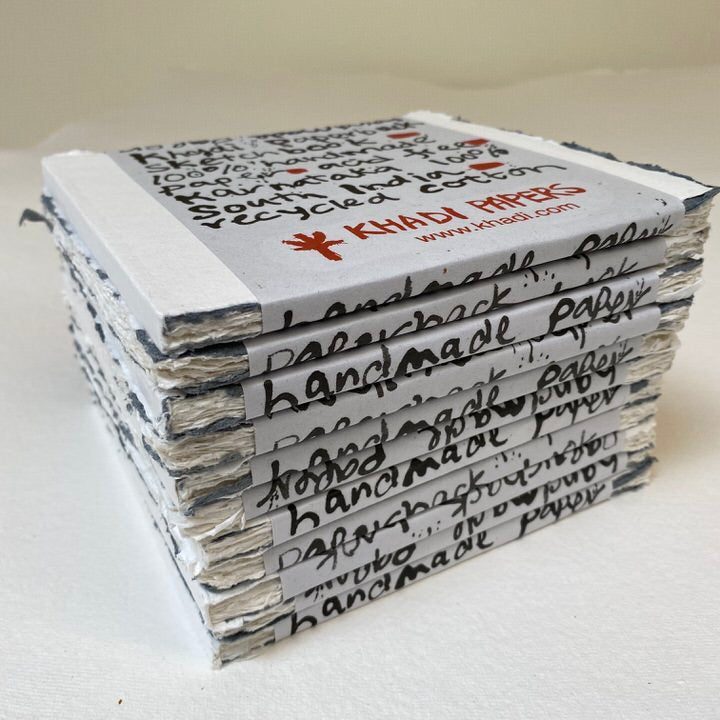 Stack of handmade paper notebooks with 'Khadi Papers' branding on a white background