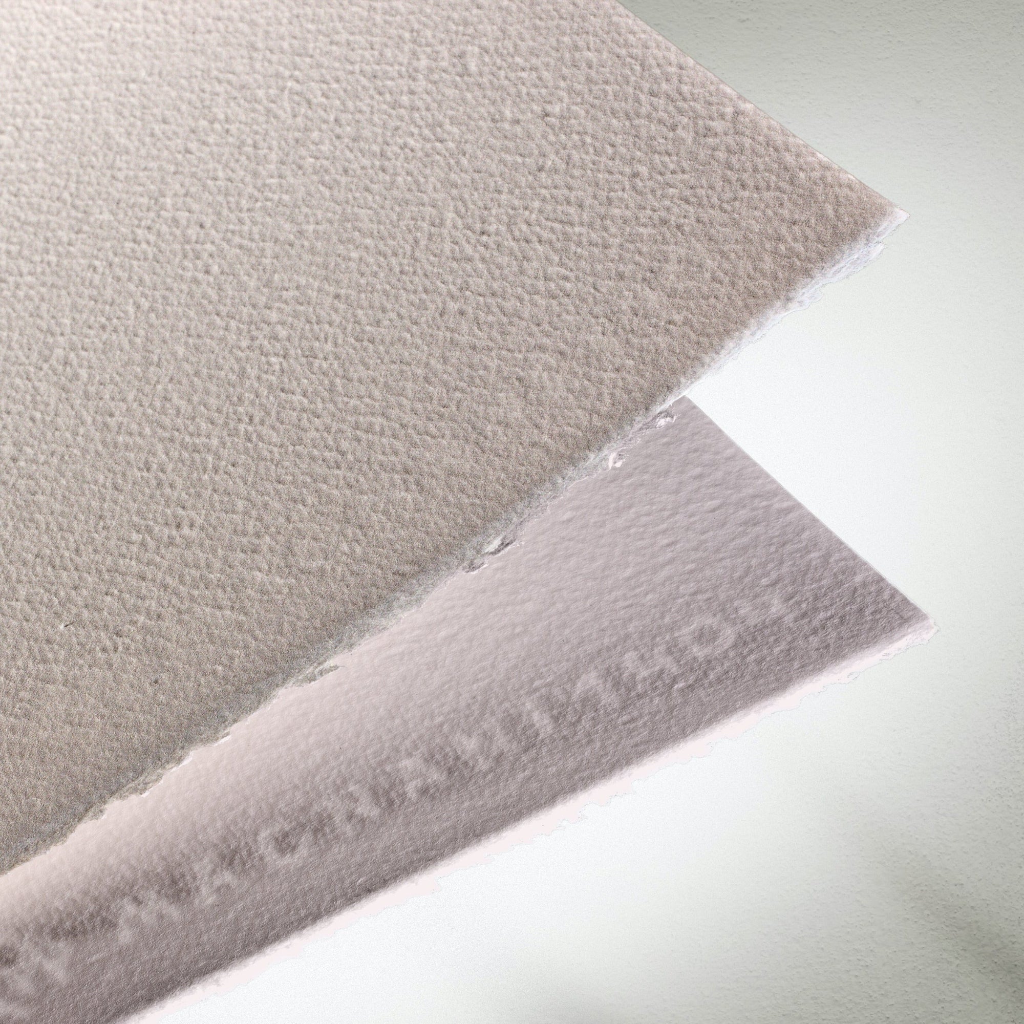 2 sheets of heavily textured Magnani Corona paper displayed one on top of the other showing opposite sides of the paper sheets.