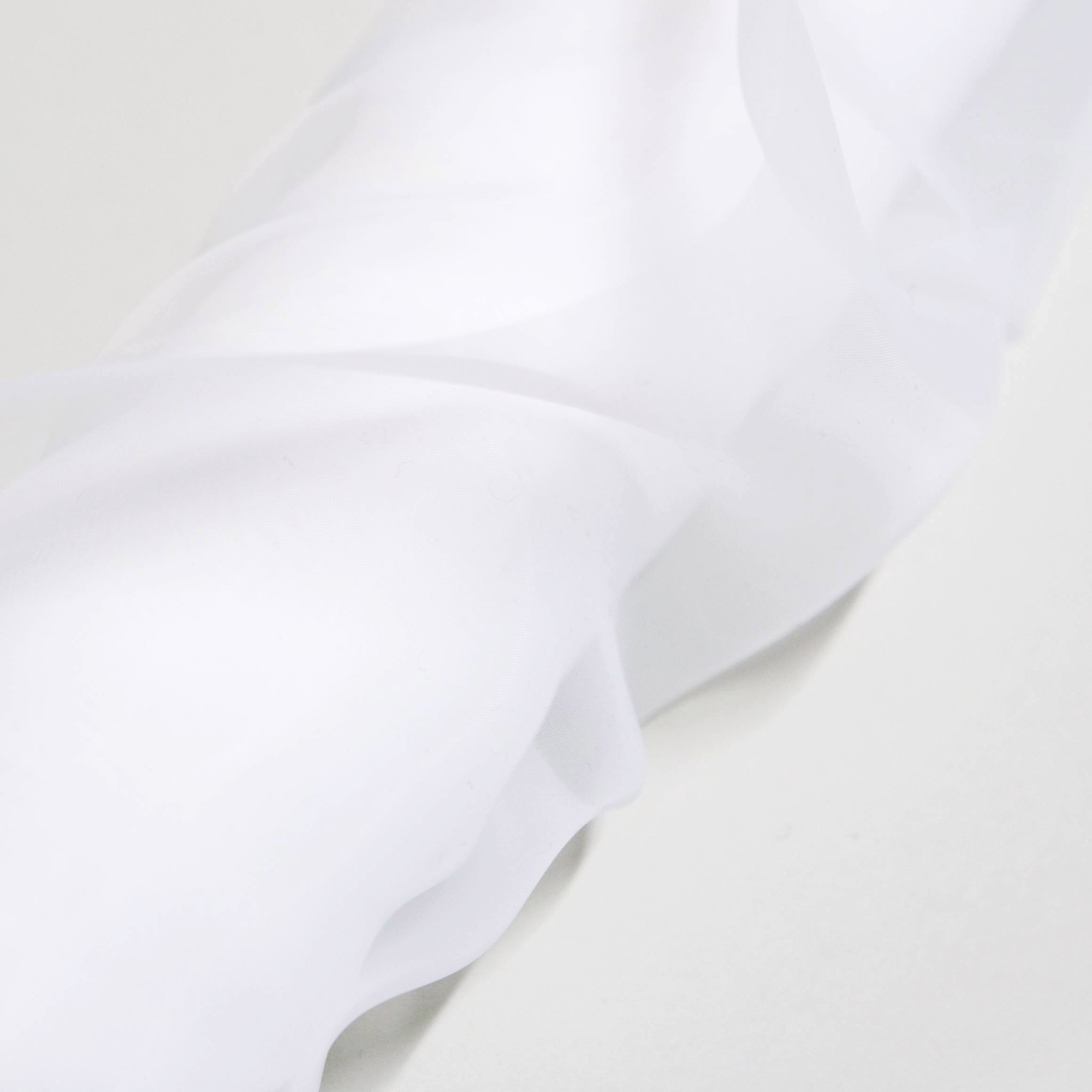 Close-up of white sheer fabric with folds on a light grey background