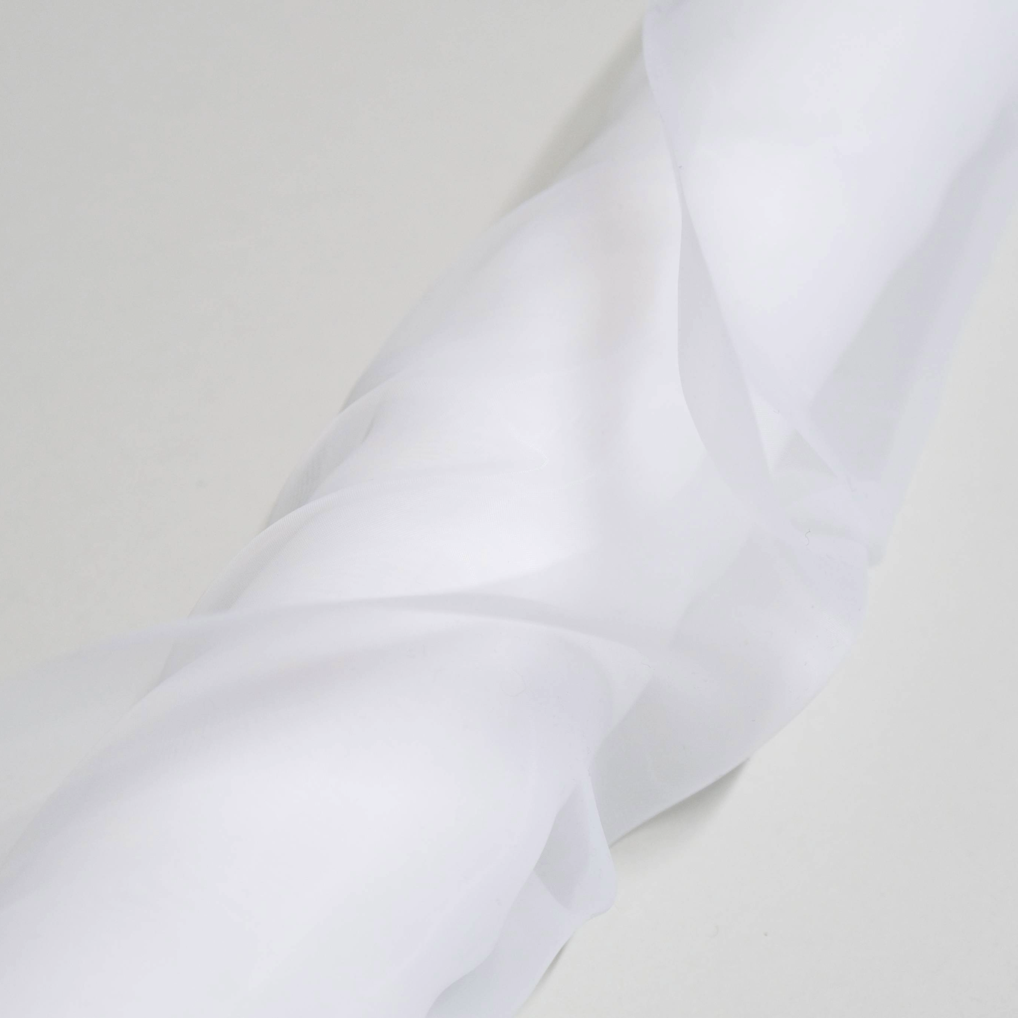 Close-up of white fabric with folds on a light grey background