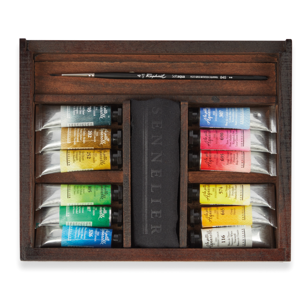 A wooden box without its lid showing compartments containing paint tubes of various colours, a black sennelier cloth and a paint brush.