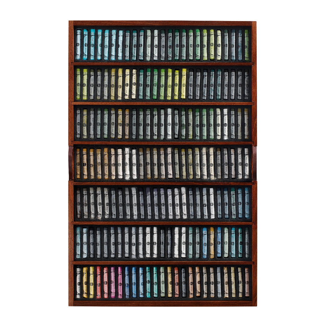 a wooden tray of soft pastels in varying colours displayed on a white background