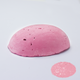 A half egg shaped pastel in a light pink tone, sitting on a white background with a drawn colour swatch.