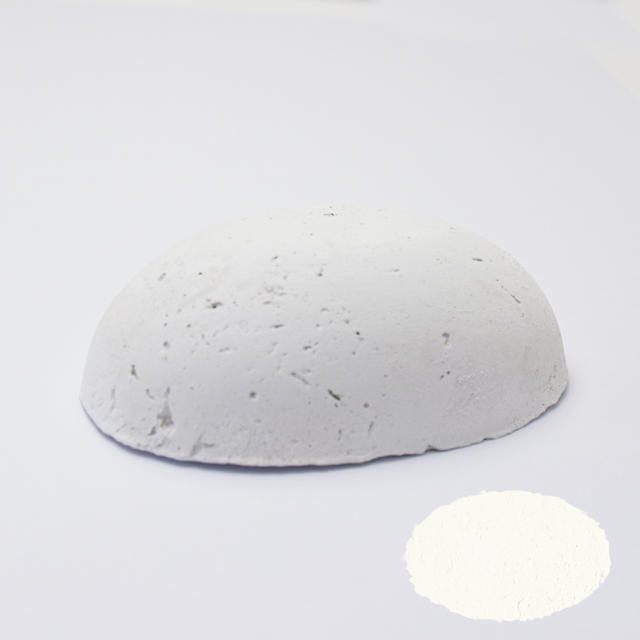 A half egg shaped pastel in white, sitting on a white background with a drawn colour swatch.
