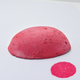 A half egg shaped pastel in a pink tone, sitting on a white background with a drawn colour swatch.
