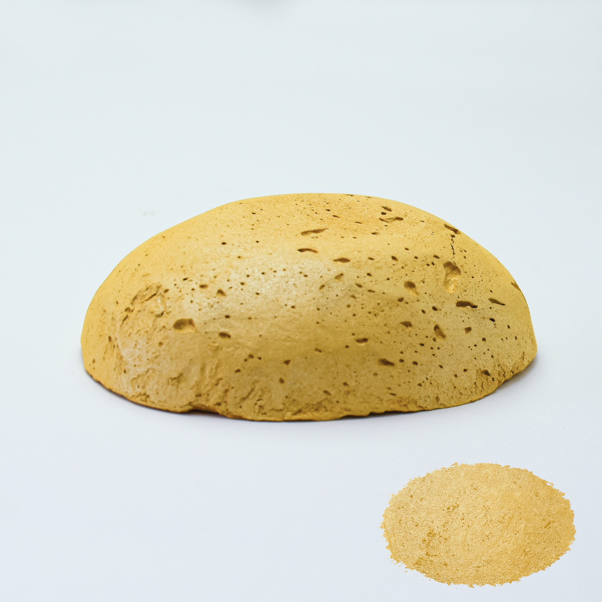 A half egg shaped pastel in a dark green tone, sitting on a white background with a drawn colour swatch.