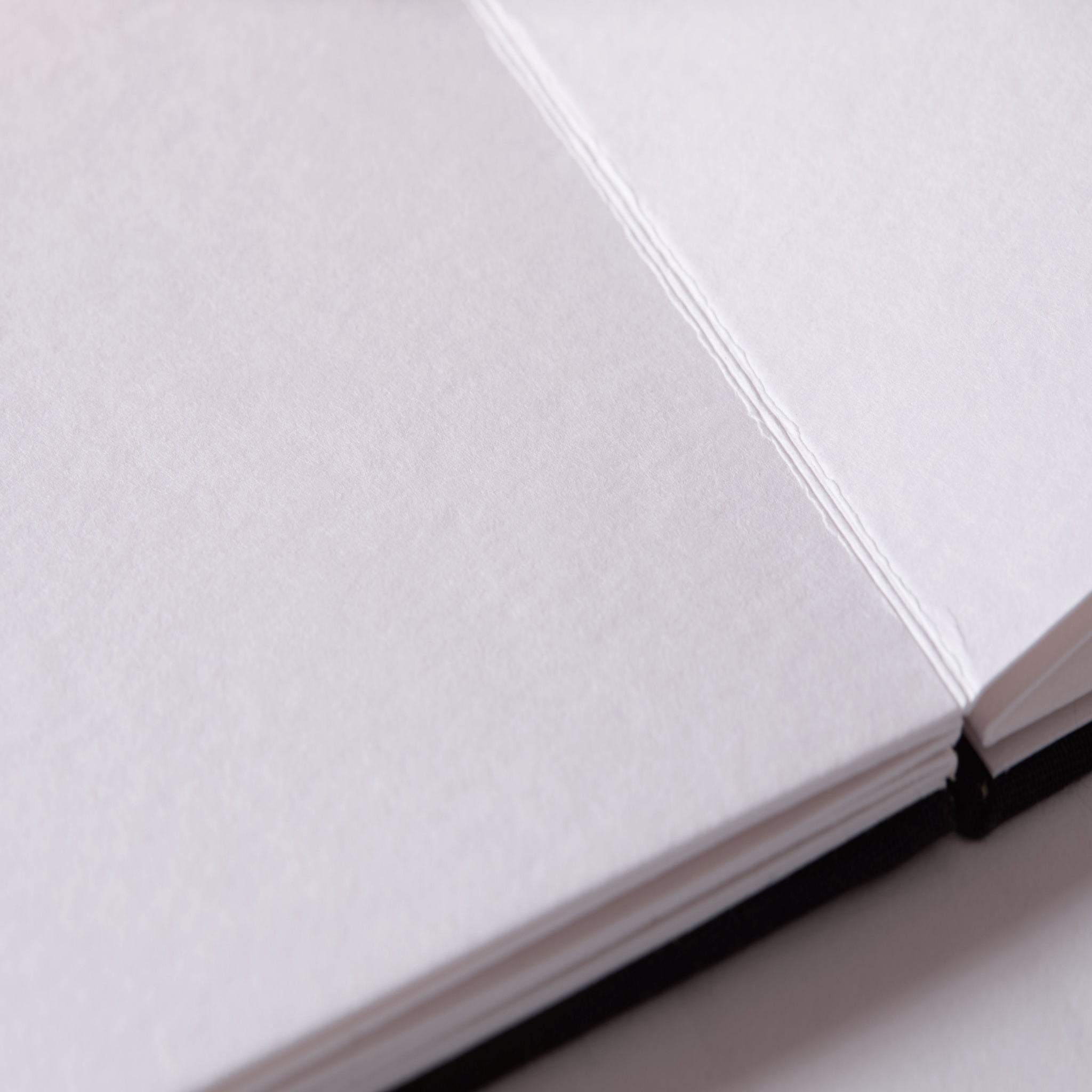 a Close up of a sketchbook with a black cover and white paper.