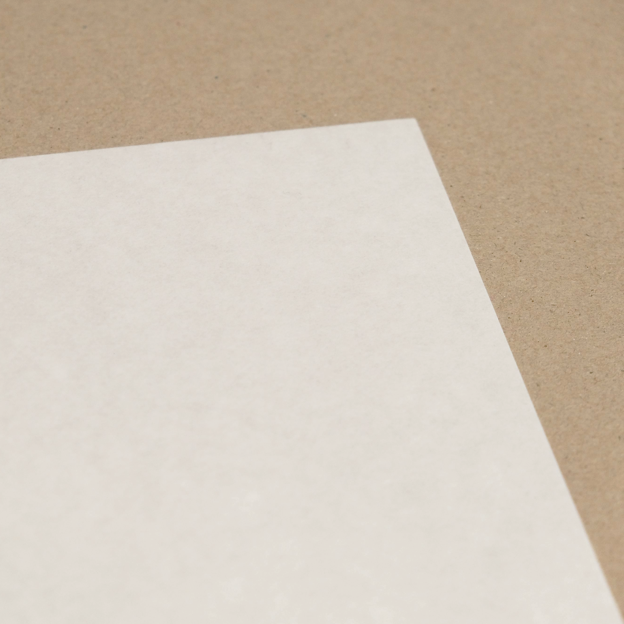 close up of a white paper sheet showing a smooth surface on a beige background