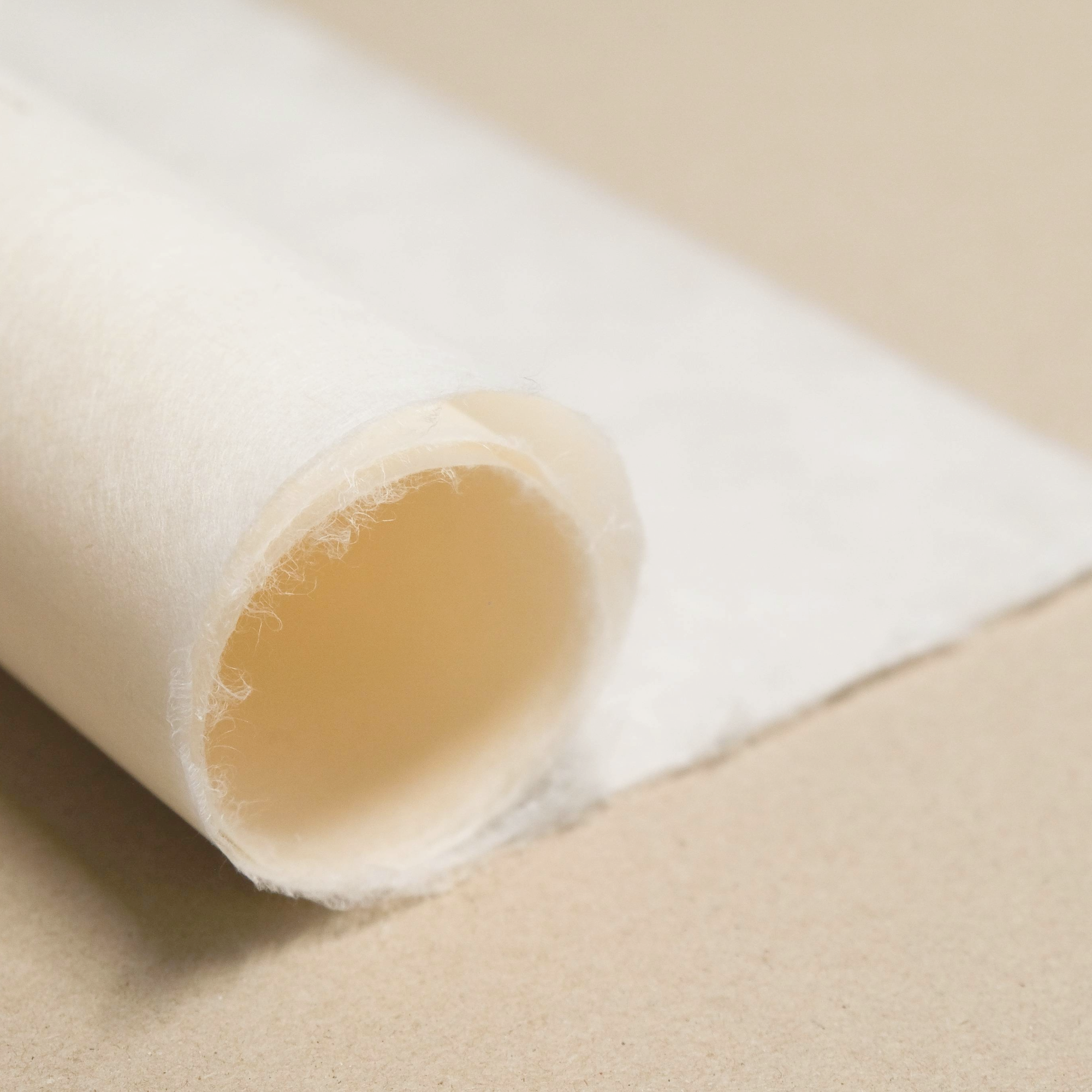 Close-up of a roll of white paper with a soft feathery edge on a brown background.