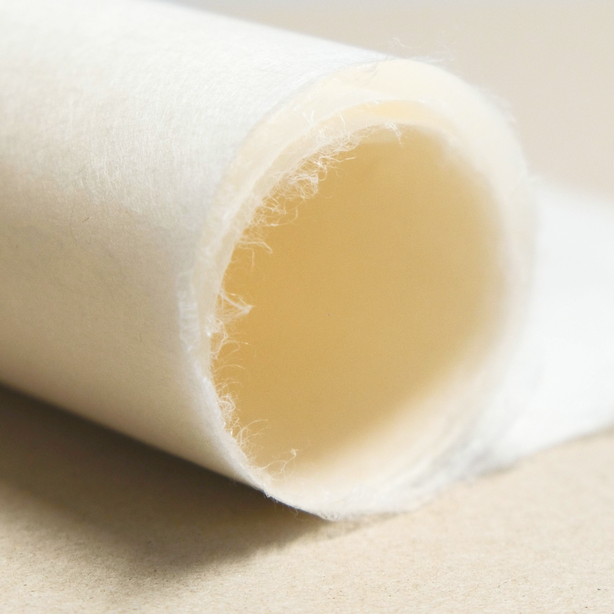 Close-up of a roll of white paper with a soft feathery edge on a brown background.