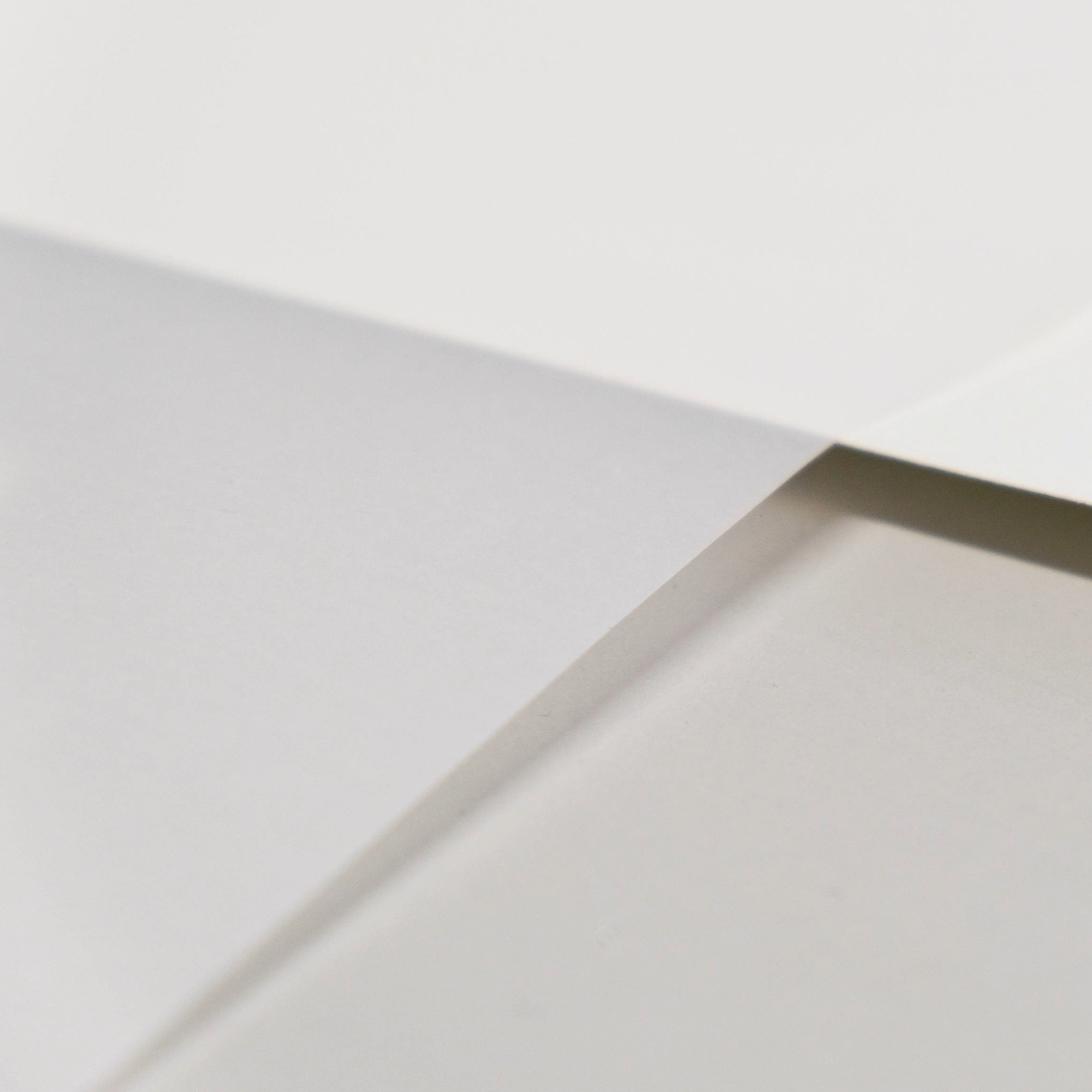 Close-up of a white paper with a transparent paper crossing over it against a grey background.