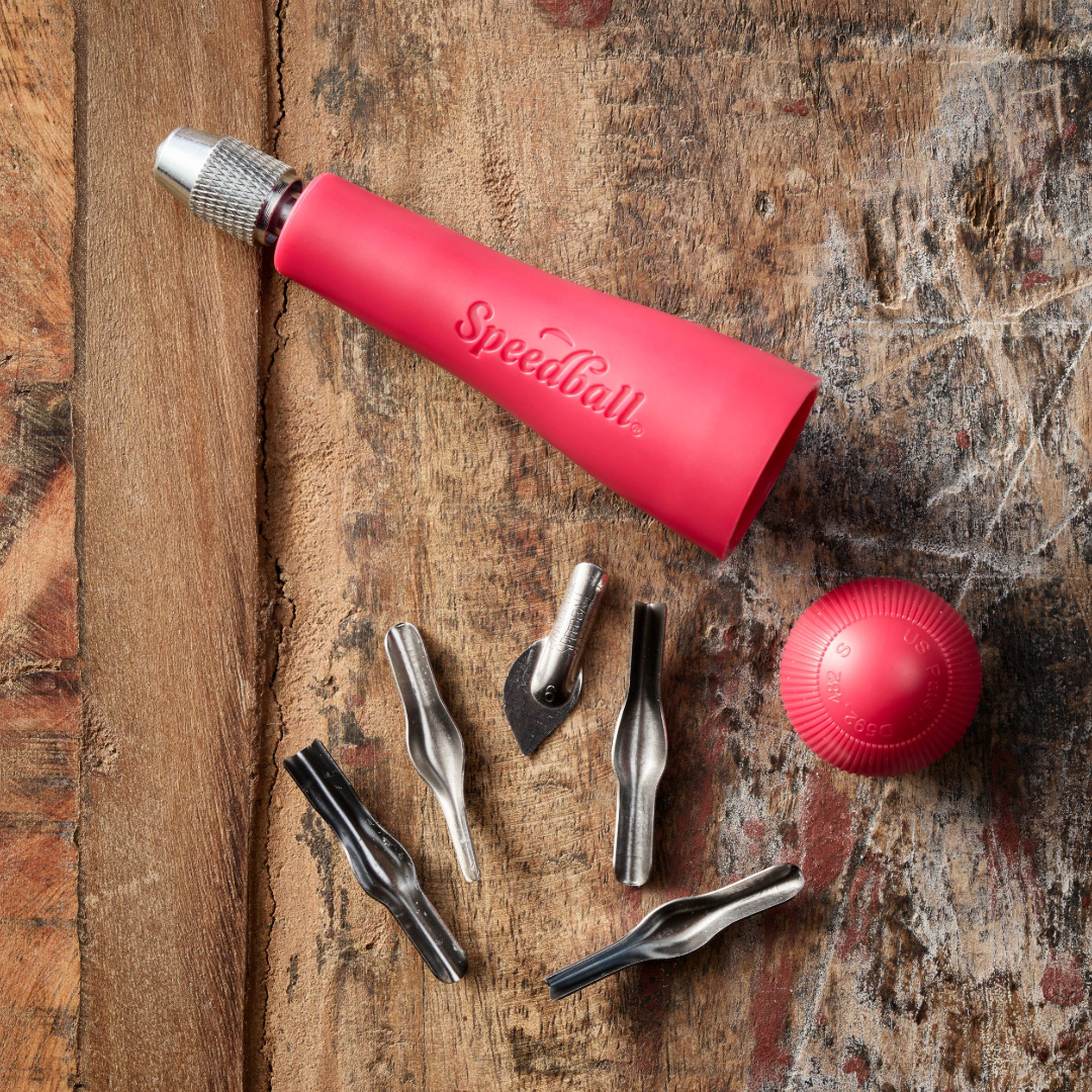 Red Speedball art tool on a wooden surface with various tool attachments.