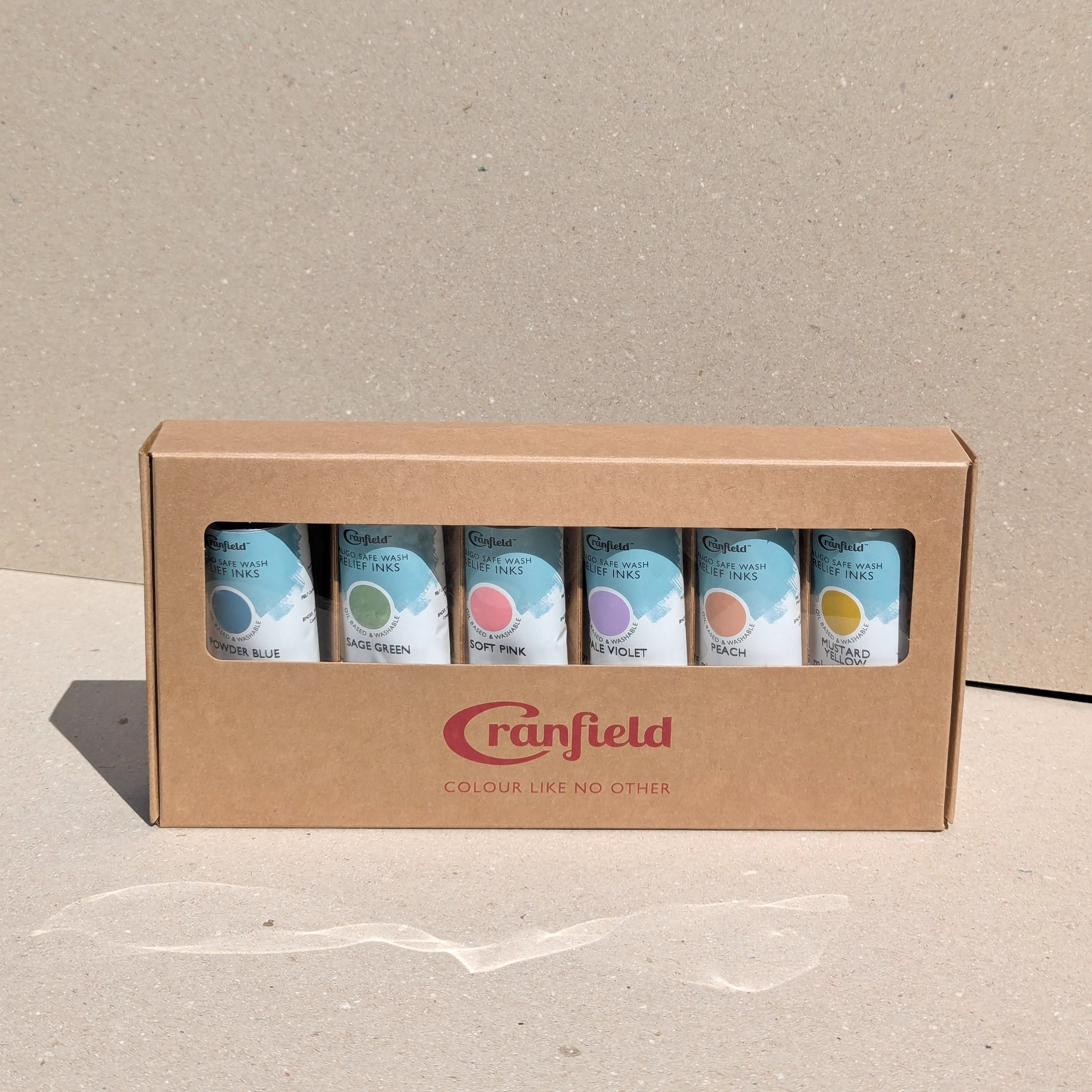 A box of Cranfield Caligo Relief soft shade inks in various colours, including powder blue, sage green, soft pink, pale violet, peach, and mustard yellow.