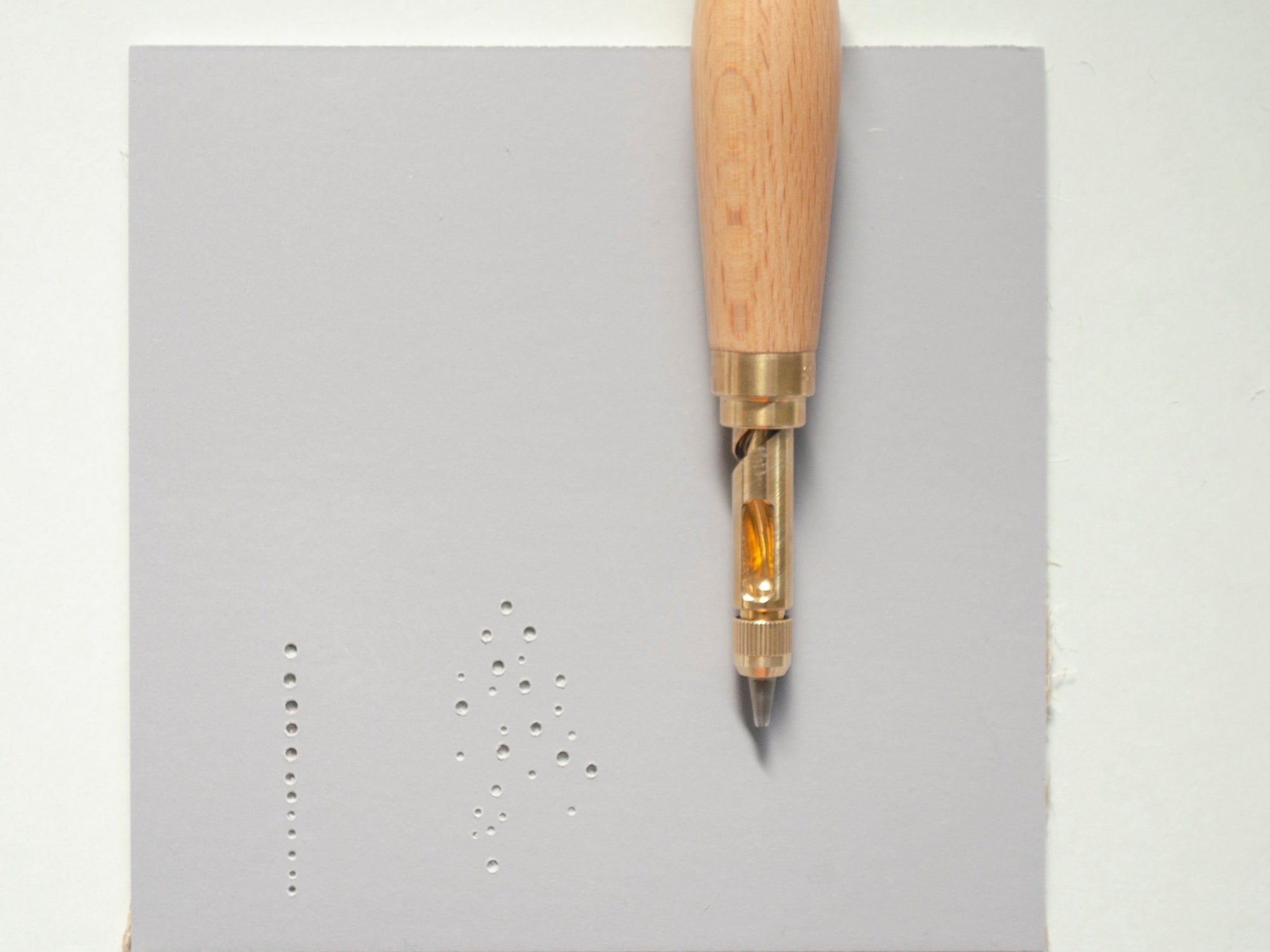 Nonaka Screwpunch Tool on a piece of lino with holes made in varying sizes.