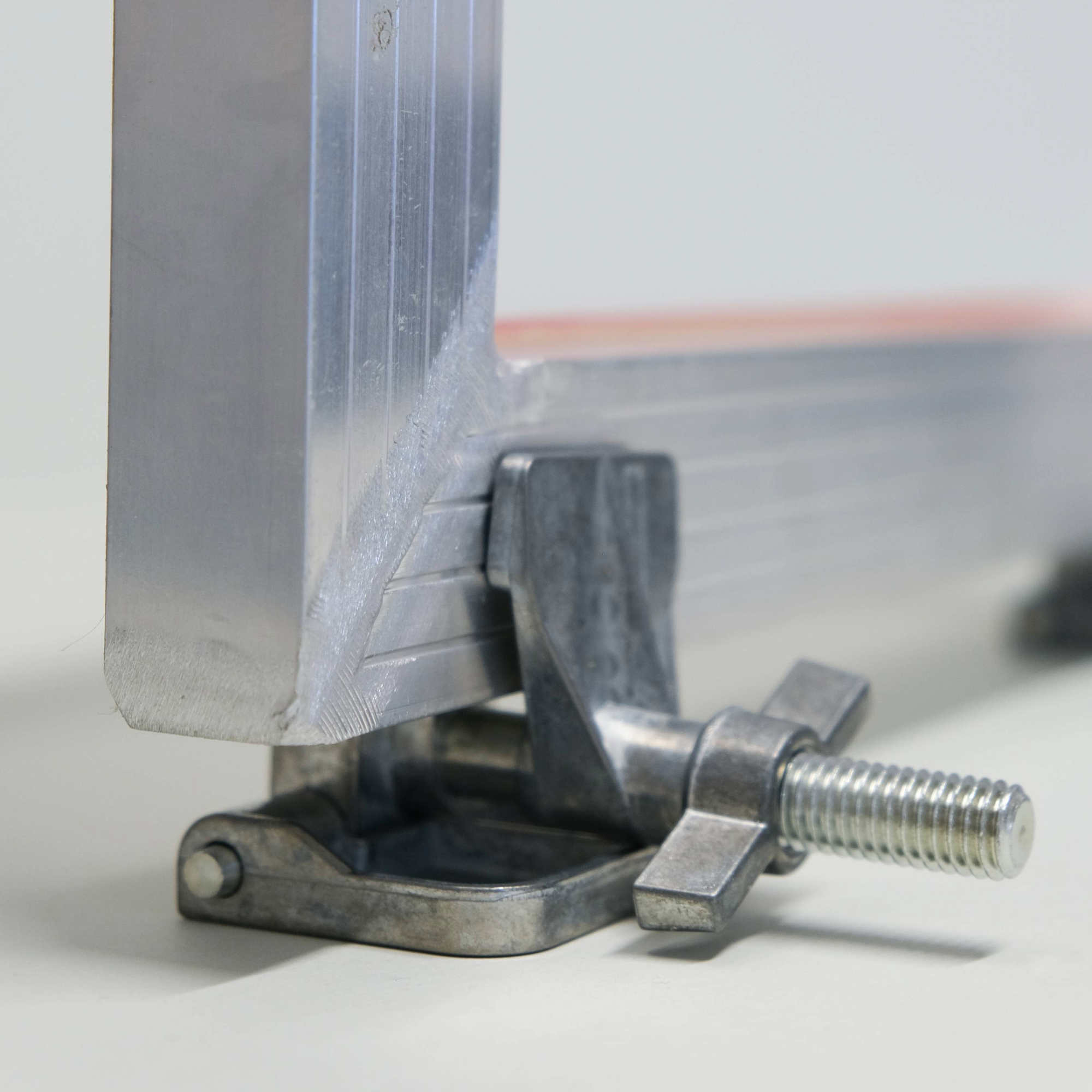 Metal hinge clamp with a bolt  attached to a aluminium screen standing up on a light background