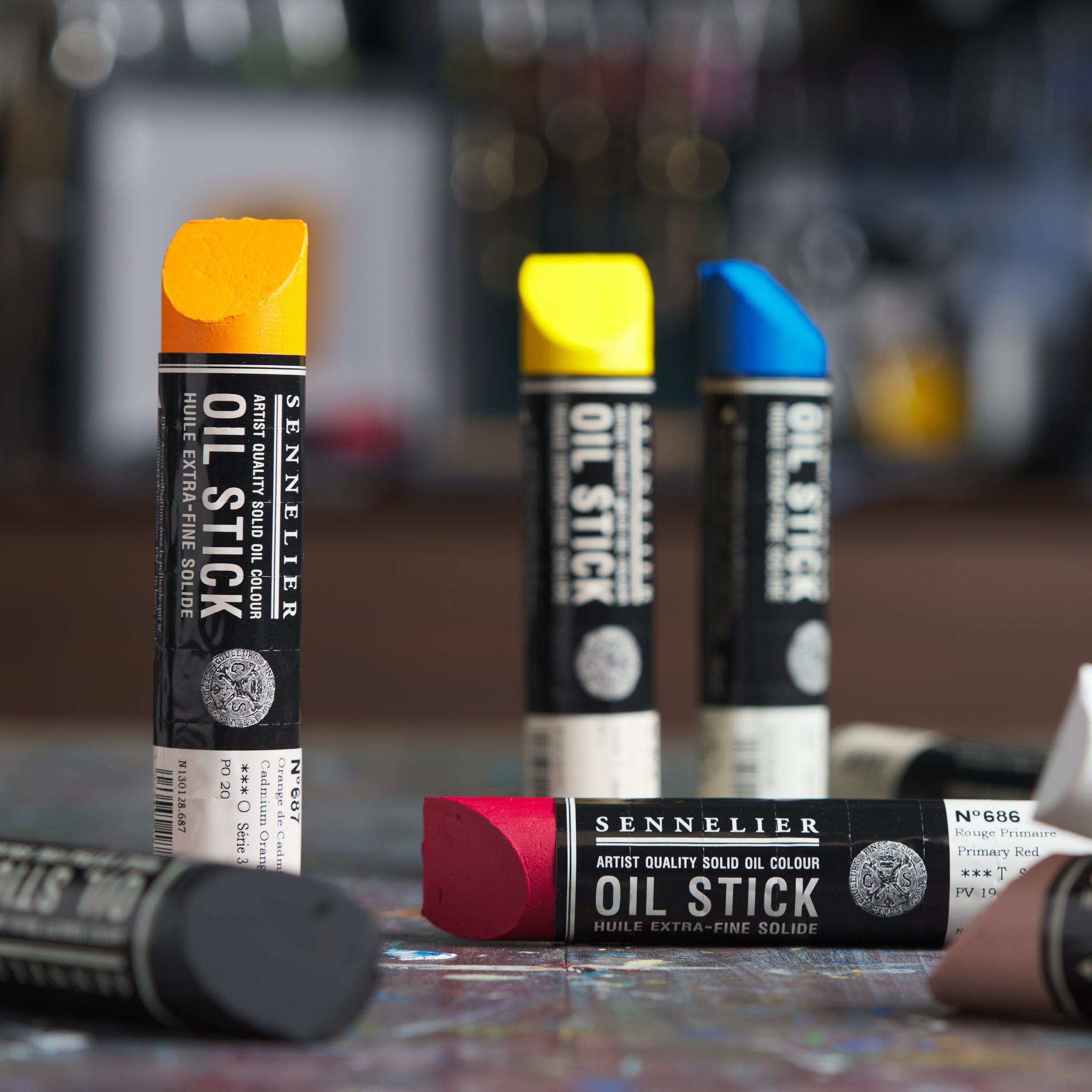 Sennelier large oil sticks with black branding standing and lying down in a studio environment.