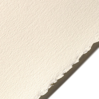 A close-up piece of Stonehenge paper in a warm white colour showing a deckled edge causing a shadow on a white background