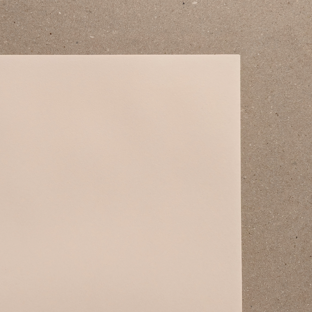 A smooth, cream-toned cartridge paper sheet placed against a textured background