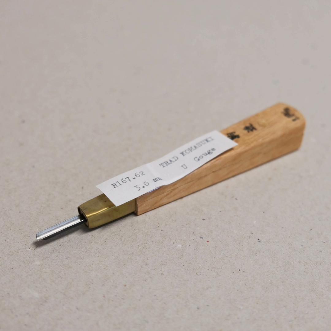 A traditional Komasuki 'U' Gouge relief tool with a wooden handle, brass ferrule and a steel blade on a light background