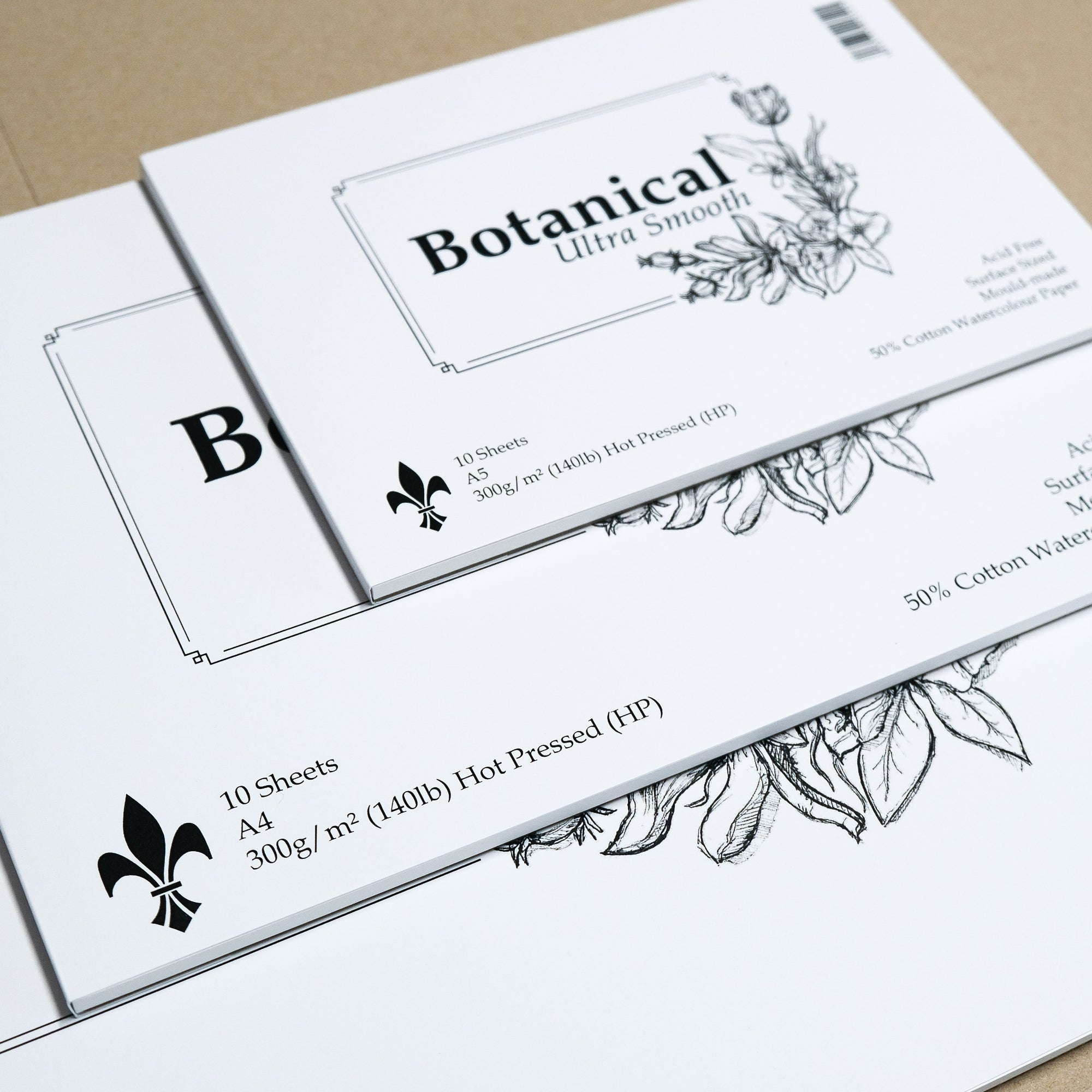Stack of 3 Botanical Ultra Smooth paper pads in varying sizes showing  simple black on white packaging with a small sketch of leaves and flowers. 