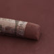 A close-up of a brown Sennelier extra soft pastel with the colour information printed on the paper wrap.