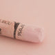 A close-up of a white Sennelier extra soft pastel on the same coloured background, with the colour information printed on the paper wrap.