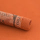 A close-up of a brown Sennelier extra soft pastel with the colour information printed on the paper wrap.