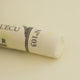 A close-up of a white Sennelier extra soft pastel. on the same coloured background, with the colour information printed on the paper wrap.