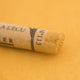 A close-up of a yellow Sennelier extra soft pastel. on the same coloured background, with the colour information printed on the paper wrap.