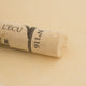 A close-up of a pale yellow Sennelier extra soft pastel. on the same coloured background, with the colour information printed on the paper wrap.