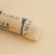 A close-up of a Sennelier extra soft pastel on a white background with the colour information printed on the paper wrap.