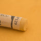 A close-up of a light orange Sennelier extra soft pastel. on the same coloured background, with the colour information printed on the paper wrap.